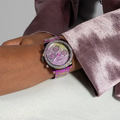 Guess Dameshorloge GW0483L5 Sol Vrouwelijk met paarse metallic afwerking en fonkelende steentjes, gedragen om een pols met roze fluwelen outfit.