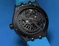Achterkant van Maurice Lacroix AI6118-DLB0J-430-H Aikon Master Grand Date heren horloge 45mm met zichtbaar automatisch uurwerk en blauwe band.